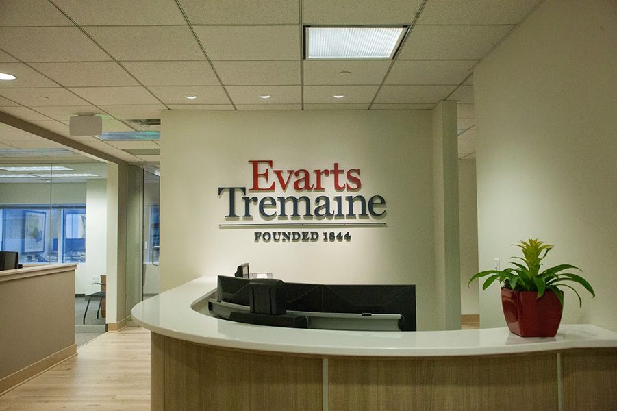 Contact - View of Front Entrance of Evarts Tremaine Office with Logo on the Wall and Rows of Computers Behind Front Desk