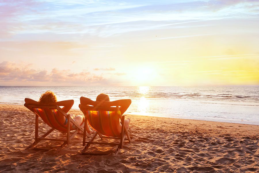 Excess Liability Insurance - Portrait of a Married Couple Relaxing on Beach Chairs While Looking at the Ocean Water at Sunset