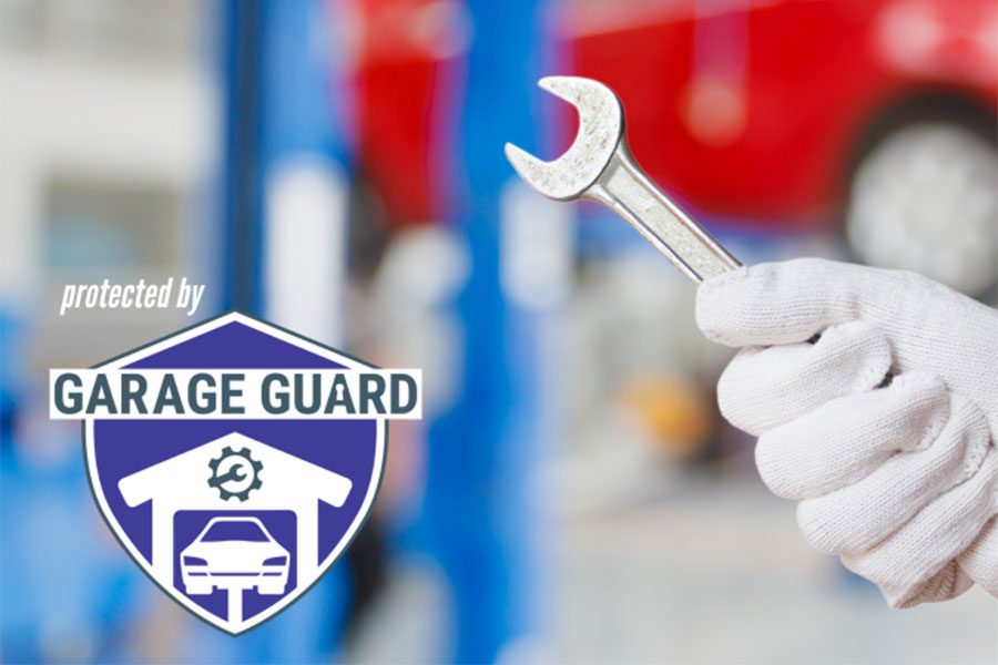 Garage Repair Shop Insurance - Blurred Photo of a Mechanic Inside a Garage Repair Shop Holding a Wrench with a Garage Guard Logo on the Left Side