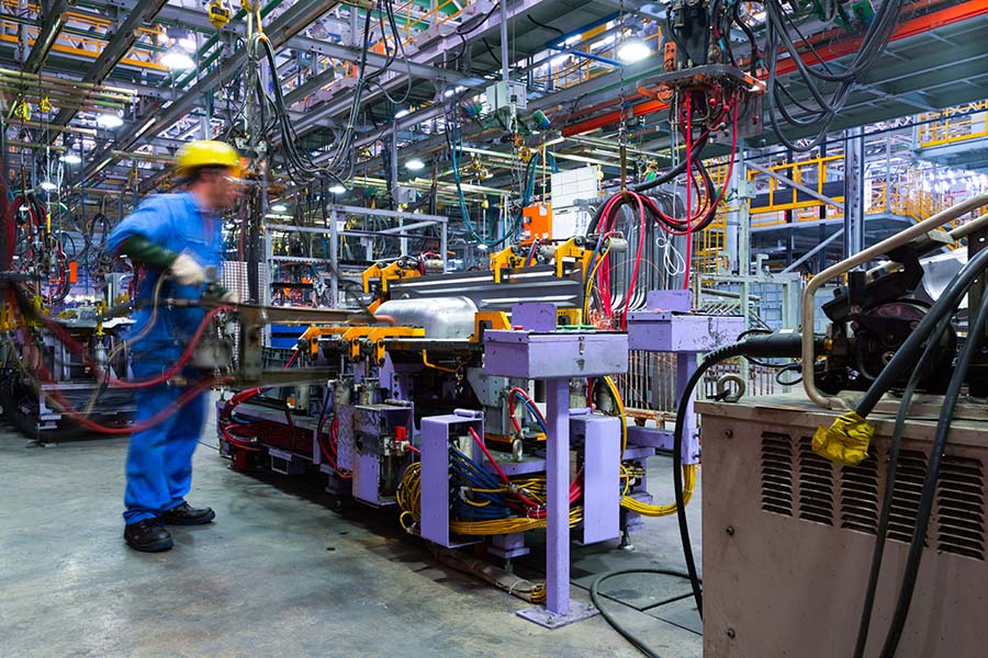 General Liability Insurance - View of a Factory Worker Working Inside a Modern Automatic Automobile Manufacturing Facility
