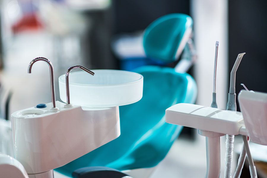 Group Dental Insurance - Closeup View of a Dentist Chair and Various Dental Tools Against a Blurred Background Inside a Dentist Office