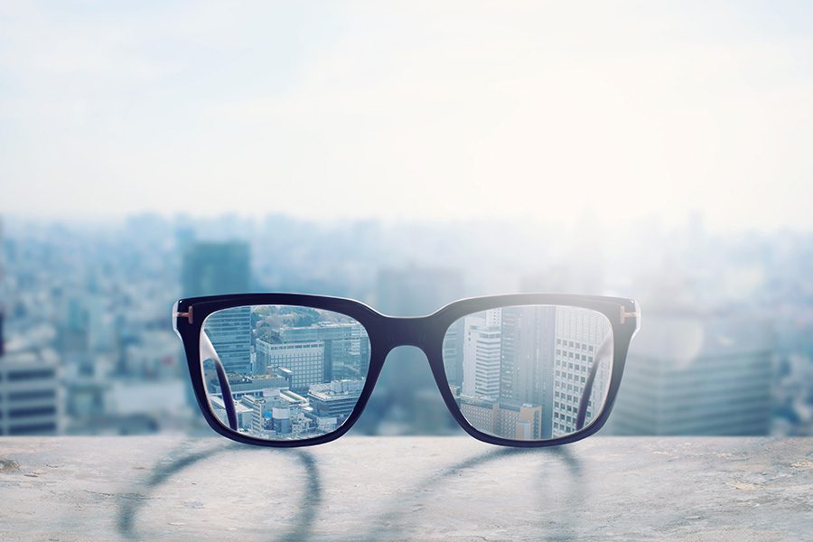 Group Vision Insurance - View of Glasses Laying on a Ledge with a Blurred City Background